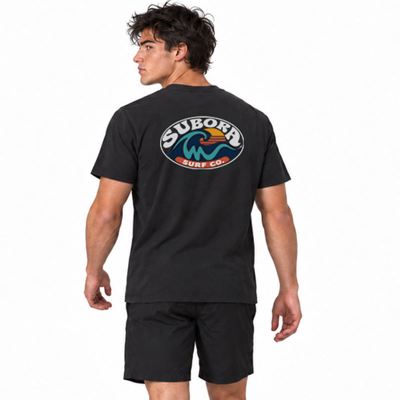Back view of the Subora Sunwash Tee in Black on a male model, showing the retro oval Subora Surf Co. badge back print with a teal wave, orange setting sun and white lettering